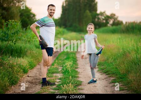 Athletic young father and little daughter do exercises in stadium. Healthy lifestyle Stock Photo