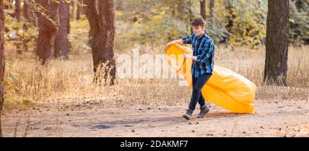 Autumn lifestyle of man inflates an inflatable orange sofa in forest. Relaxing and enjoying life on air bed banner format Stock Photo