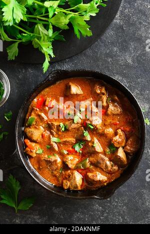 Cooked chicken livers with vegetables in frying pan over black stone background. Top view, flat lay Stock Photo