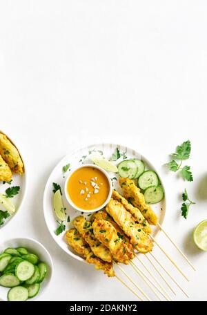 Chicken satay with peanut sauce. Grilled chicken skewers served with peanut dipping sauce. Tasty meal for dinner or party appetizers. Light background Stock Photo