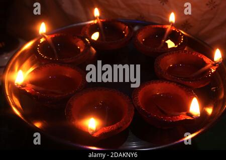 Traditional clay diya lamps lit during diwali celebration, Decoration of beautiful lamps of Indian aromatic earthenware in night, Selective Focus. Stock Photo