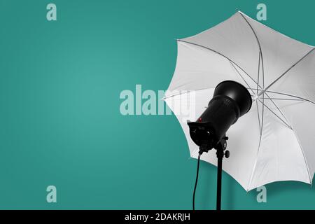 photo studio flash strobe with white umbrella on stand on cyan background. lighting equipment. copy space Stock Photo