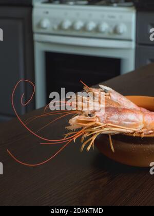 Fresh prawns on the kitchen table in a bowl. Cooked fresh giant prawns. Stock Photo