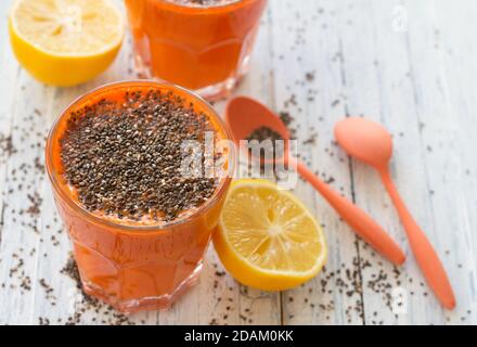 Carrot cocktail with lemon and chia seeds in a glasses on a light blue background, selective focus. Healthy delicious drink Stock Photo