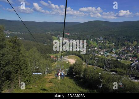 People travelling on a chairlift, summer Aerial view of Harrachov town (Harrachov, Czech republic) Stock Photo