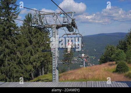 People travelling on a chairlift, summer Aerial view of Harrachov town (Harrachov, Czech republic) Stock Photo