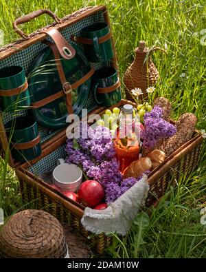 Pastry, bread, apples and other food in a picnic basket on grass Stock Photo