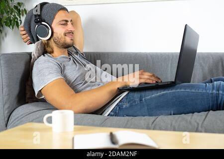 Handsome young business caucasian man working at home using laptop and talking with mobile phone feeling relaxed Stock Photo