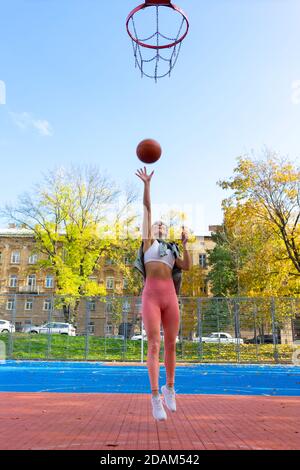 Female basketball player in jump throws the ball into the basket Stock Photo