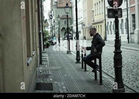 Wroclaw, Poland - May 10, 2019: A man sitting at an entrance of a house smoking in the polish old town of city center. Stock Photo