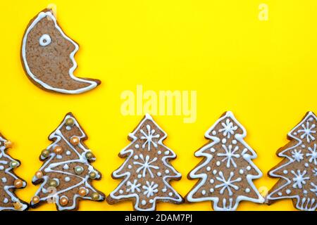 Christmas cookies on a yellow background. New Year composition with gingerbread and copy space. Homemade gingerbread cookies with glaze in the shape o Stock Photo