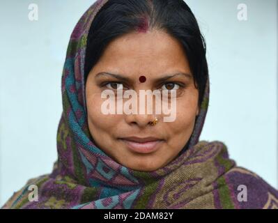 Married young Indian Hindu woman with red sindoor, red bindi and gold nose ring covers her head with a warm shawl and poses for the camera. Stock Photo