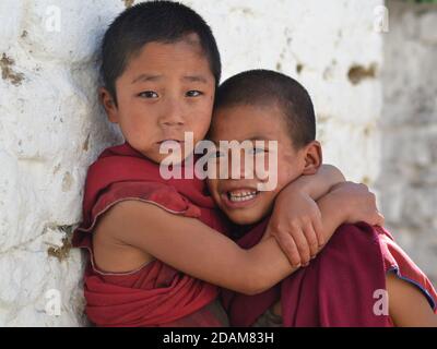 Two naughty little Tibetan Buddhist boy monks hug each other and pose for the camera inside Tawang Monastery. Stock Photo