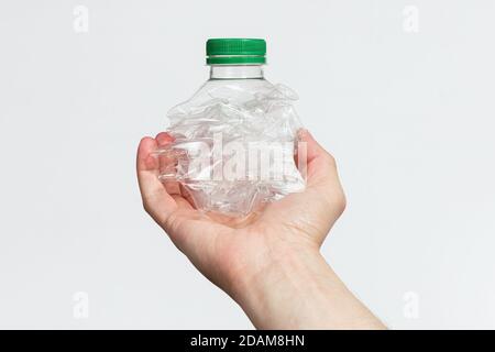 Hand holding smashed empty plastic bottle isolated on a white background Stock Photo
