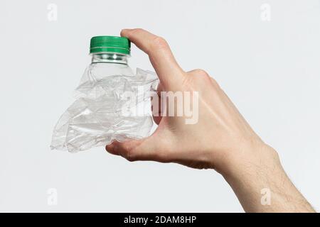 Hand holding smashed empty plastic bottle isolated on a white background Stock Photo