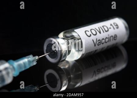 COVID-19 vaccine on black close-up, syringe and bottle with vaccine for coronavirus cure. Concept of corona virus research, treatment, injection, shot Stock Photo