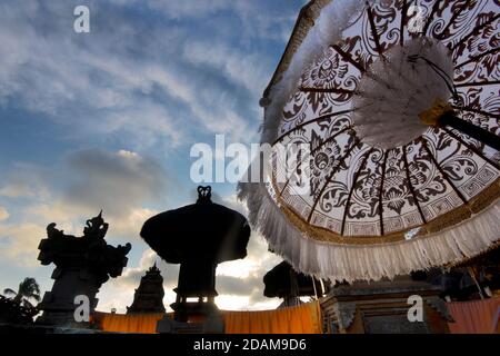 Silhouettes of temple buildings and backlit parasols at a temple, during the Galungan festival.  Ubud, Bali, Indonesia Stock Photo