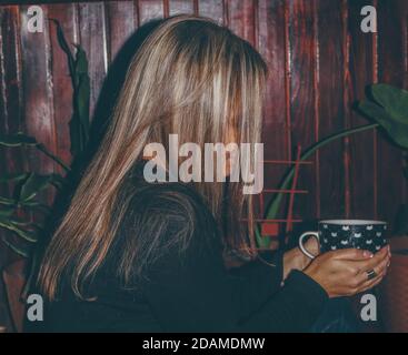 A woman drinking coffee alone in the dark Stock Photo