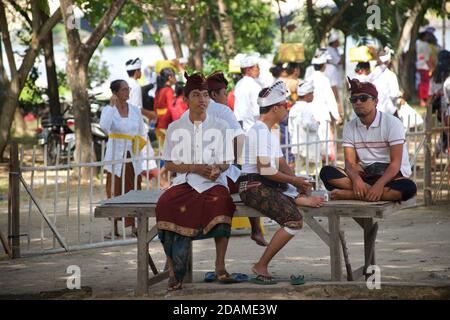 Balinese men in traditional festive attire relaxing at Sakenan temple, Bali, Indonesia during Galungan festivities. Stock Photo