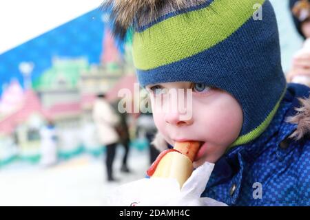 Child eating hot dog on street in winter Stock Photo