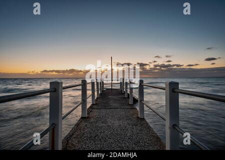Looking out over a pier against the ocean, a dusk horizon sky Stock Photo