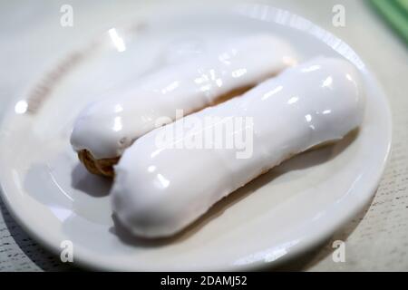 Two vanilla eclairs with icing on plate Stock Photo