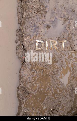 the word mud imprinted in wet dirt road surface and puddle - close-up with selective focus in flat lay perspective. Stock Photo