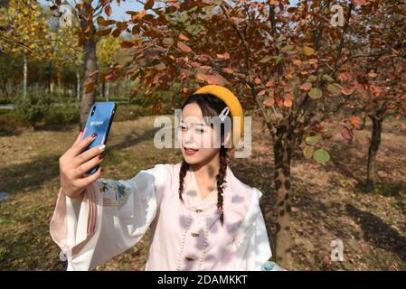 (201114) -- HEZE, Nov. 14, 2020 (Xinhua) -- Sun Yan, an online clothes store owner, presents the costume she designed in the fusion of the traditional clothing of the Han ethnic group that is generally called Hanfu via live streaming, in Sunzhuang Village in Caoxian County of Heze City, east China's Shandong Province, Nov. 10, 2020. Sunzhuang Village thrives on e-commerce business. Among some 760 households in the village, more than 560 run online clothes stores on Taobao.com, Alibaba's main e-commerce site. The village's sales volume of costumes exceeded 200 million yuan (about 30.22 million Stock Photo