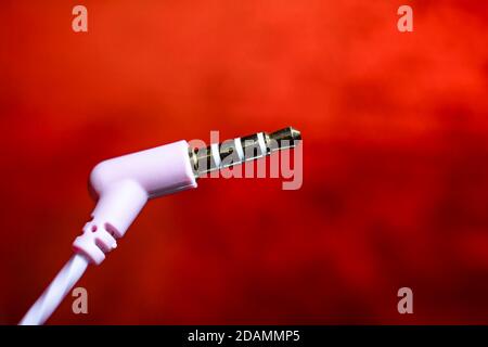 headset plug close-up on a red background macro photo. Stock Photo