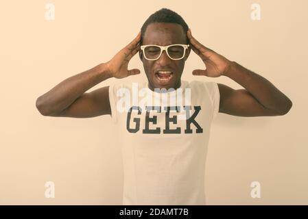 Studio shot of young black African nerd man wearing Geek shirt while having headache against white background Stock Photo
