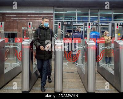 Moscow. Russia. October 29, 2020. Passengers pass through automatic turnstiles at the Moscow metro station. On the faces of people, protective masks Stock Photo