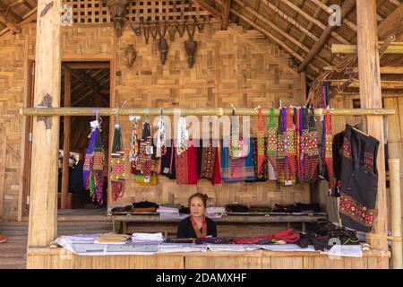A Nagamese shopkeeper selling local traditional merchandise in a woodwn stall at Hornbill festival at Kisama Nagaland India on 4 December 2016 Stock Photo