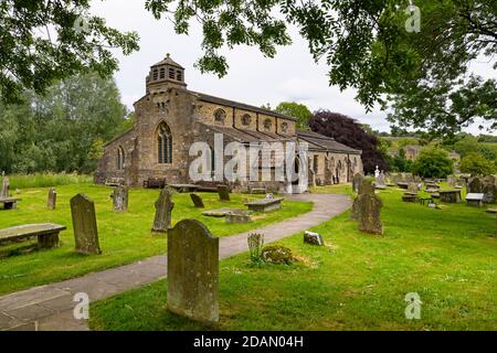 Exterior of historic scenic St Michael & All Angels Church, churchyard memorials & pathway leading to entrance - Linton, Yorkshire Dales, England, UK. Stock Photo