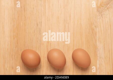 Three chicken egg on a light brown wooden background, Top view with copy space Stock Photo