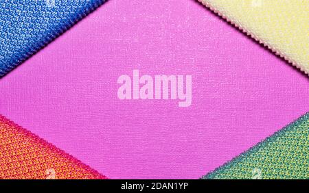 Colorful cleaning sponges placed in corners, diamond shape borders on plain pink background with copy space. Stock Photo