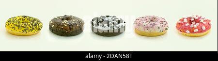 Banner size photo with multi colored different flavored glazed sprinkled donuts arranged in a row isolated on white background Stock Photo