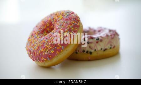 Close up of two delicious sweet tasty colorful donuts glazed and sprinkles isolated on white background Stock Photo