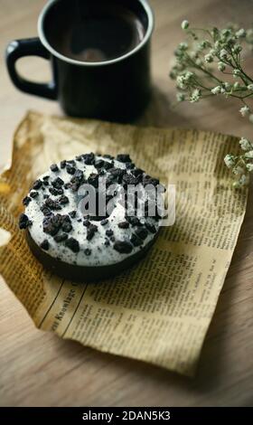 Close up view of delicious tasty glazed sprinkled with chocolate donuts with a fresh hot cup of coffee on table Stock Photo