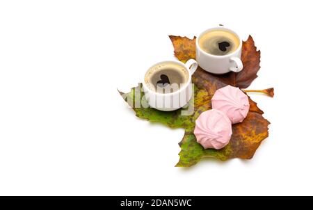Romantic fall still life. Two coffee cups with heart shapes on the foam and rose marshmallows on a large maple leaf isolated on white. Top angle view, Stock Photo