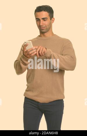 Young handsome Iranian man using mobile phone Stock Photo