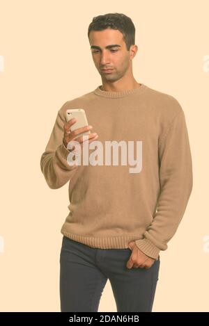 Young handsome Iranian man using mobile phone Stock Photo