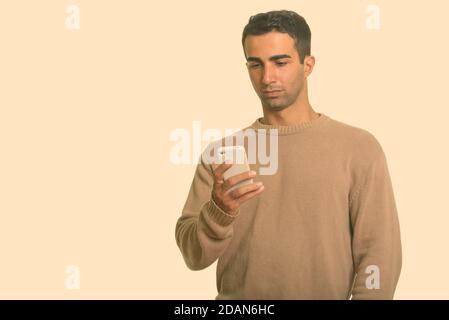 Young handsome Iranian man using mobile phone Stock Photo