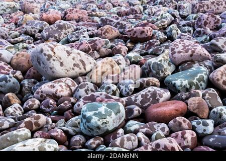Pebbles on the seashore during a rain storm, showing the patterns made by the rain drops Stock Photo