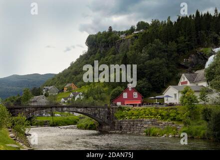 Typical Norwegian house near one of the most popular waterfalls in Norway - Steinsdalsfossen, on the Fosselva river in western Norway Stock Photo