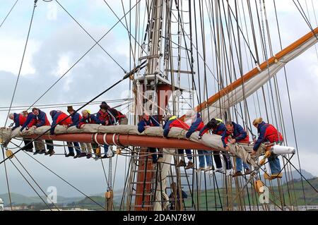 Crew aloft practicing   reefing in the main -course yard on Tall  Ship TYS The Prince William while berthed at Horta Azores Stock Photo