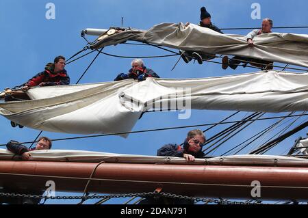 Cew aloft at work  reefing in the Course, Lower Topsail, Upper Topsail on  Tall  Ship TYS The Prince William, Atlantic Ocean Stock Photo