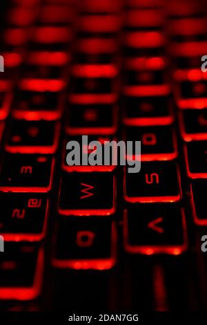 Vertical shot of a red, backlit keyboard in a dark setting Stock Photo