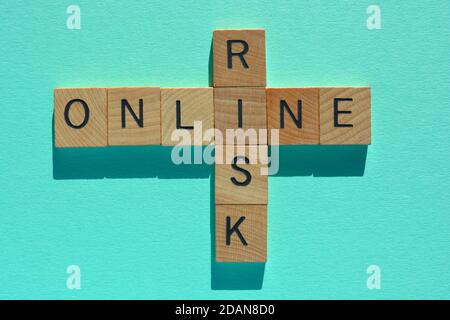 Online Risk, words in wooden alphabet letters in crossword form isolated on turquoise background Stock Photo
