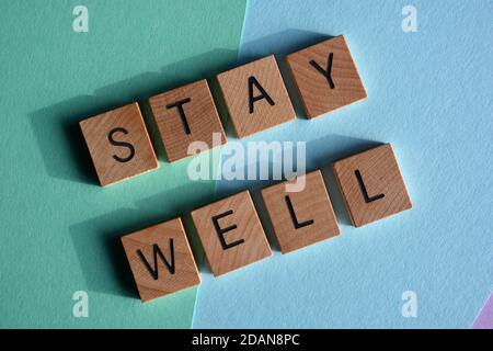 Stay Well, words in wooden alphabet letters isolated on blue background Stock Photo