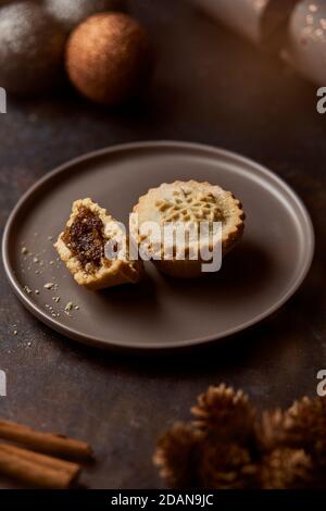 Mince pies on a grey plate surrounded by Christmas decorations Stock Photo